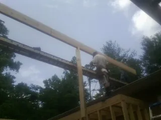 Carpenter setting a ridge beam over a new addition frame — Ice Dam Removal by Roofing Brothers in Riverview