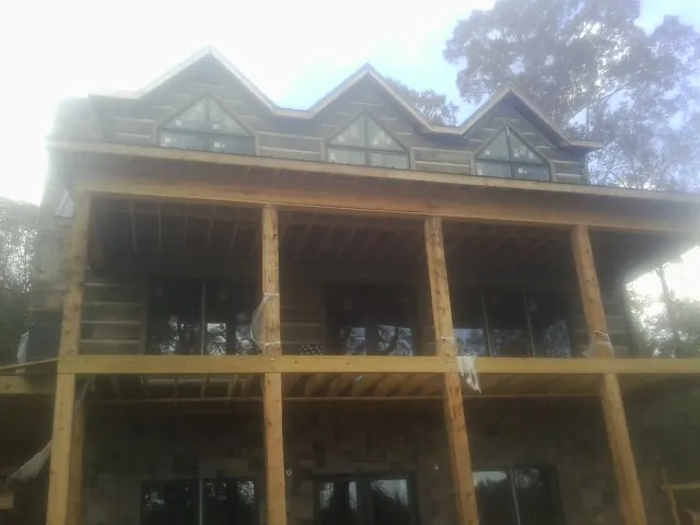Dormers and porch framing on a large log home under construction — Roof Coating work by our crew in Riverview
