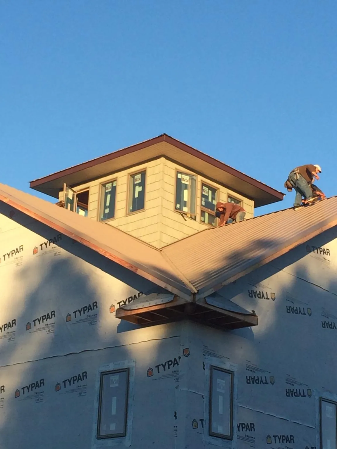 Roofers working around a rooftop cupola on a new metal roof at sunset — Roof Waterproofing in Riverview by Roofing Brothers